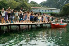 a group of people are standing on a dock with their arms in the air as they dance