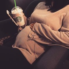 a pregnant woman holding a starbucks drink in her lap