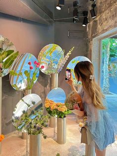 a woman taking a selfie in front of mirrors with flowers and plants on them