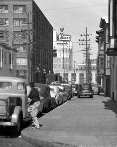 an old black and white photo of cars parked on the street