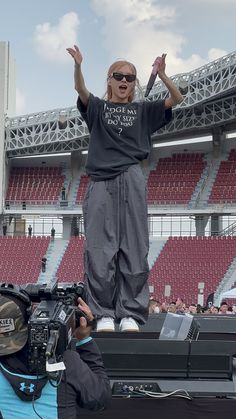 a man standing on top of a stage with his hands in the air and people behind him