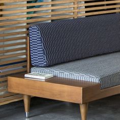 a couch sitting on top of a wooden table next to a wall covered in slats