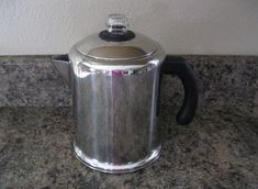 a stainless steel tea pot sitting on top of a granite counter next to a wall