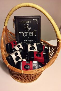 a basket filled with cameras sitting on top of a table next to a sign that says capture the moment