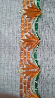 an orange and green ribbon is on top of white fabric