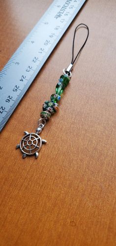 a close up of a piece of jewelry on a wooden table next to a ruler