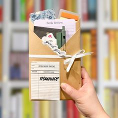 a person holding up a book in front of a bookshelf