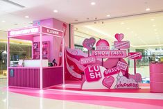 a pink and white store with lots of signs on the side of it's display