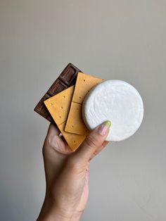 a hand holding a piece of cheese and crackers on top of eachother