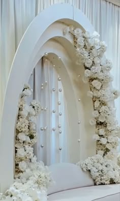 a white wedding arch with flowers and pearls