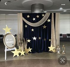 a stage set up with gold stars and blue drapes for a wedding or special event