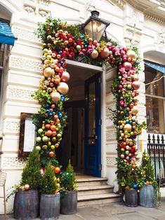 an entrance decorated with christmas ornaments and potted plants in front of a white building