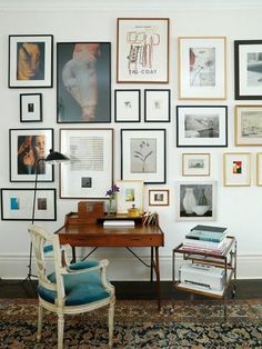 a room with many pictures on the wall and a desk in front of some chairs