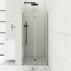 a white tiled bathroom with a walk in shower next to a sink and towel on the floor