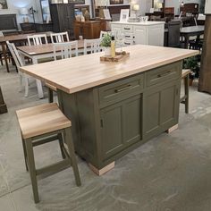 a kitchen island with two stools in front of it and lots of chairs around it