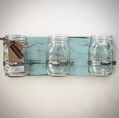 three mason jars are hanging on a wall with a tag attached to the jar holders