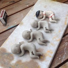 five small ceramic figurines laying on top of a piece of wood next to a lighter