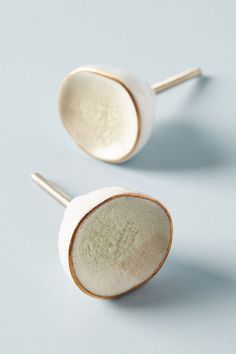 two white ceramic spoons sitting next to each other on top of a blue surface