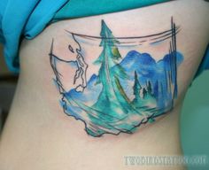 a woman's stomach with a watercolor tattoo on it