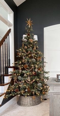 a small christmas tree in a basket on the floor next to a stair case and stairs