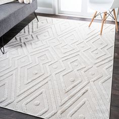 a living room with a gray couch and white rug