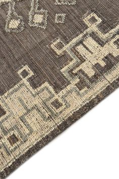 a brown and beige area rug with an intricate design on the bottom, in front of a white background