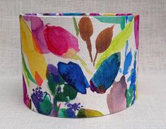 a colorful flower print lamp shade on a white tablecloth with pink, blue and green flowers