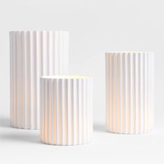 three white vases sitting next to each other on top of a table in front of a white background