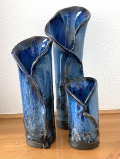 three blue vases sitting on top of a wooden table