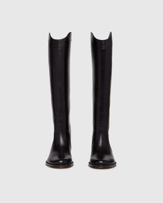 Raina is our take on the classic riding boot. Crafted from a super durable yet luxuriously soft black leather, this timeless straight shaft tall boot is designed with a curved topline that dips at the front and back for a flattering look, western-inspired pattern and stitch detailing, an extended leather welt with tonal stitch details, and a black leather stacked 20mm heel for a slight amount of lift. The classic menswear-inspired details on the outsole include stitching and half toplift for an Black Tall Boots Women, Riding Boot Outfit, Womens Tall Black Boots, Tall Boots Outfit, Riding Boot Outfits, Tall Western Boot, Capsule Wardrobe Women, Classic Menswear, Womens Riding Boots