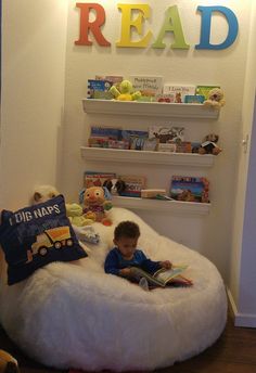 a little boy reading a book in a bean bag chair