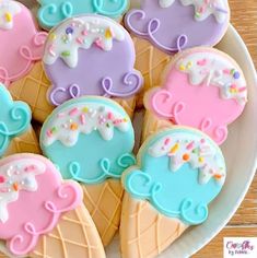 decorated cookies in the shape of ice cream cones on a plate with sprinkles