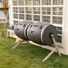 two large barrels sitting on top of a wooden stand in front of a building with windows