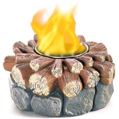 a fire pit made out of rocks and logs with flames coming out of the top