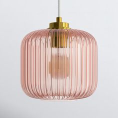 a pink glass pendant light hanging from a ceiling fixture with a gold colored metal fitting