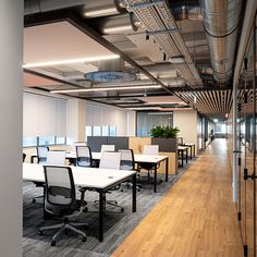 an office with wooden flooring and white desks in the center, along with glass walls