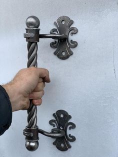 a hand is pulling the handle on an ornately designed metal doorknoble