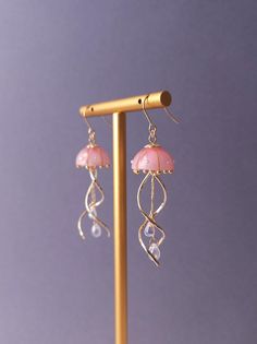 "Introducing our stunning Jellyfish Earrings, crafted with utmost care and fashioned with a unique blend of resin, curved metal charms, and delicate teardrop beads. These enchanting earrings capture the graceful movement of jellyfish in a captivating design that is sure to turn heads. Each intricately detailed jellyfish is meticulously molded from resin, showcasing their ethereal beauty. The curved metal charms add a touch of elegance and whimsy, perfectly complemented by the shimmering teardrop beads that dangle gracefully.  Perfect as a gift for ocean lovers or as a treat for yourself, these earrings are a must-have addition to any jewelry collection. We use Japanese-made high quality resin that is durable, clear and less prone to yellowing. ➣SIZE Drop Length(Approx.) : 5.5 cm / 2.17 inc Cute Earring Ideas, Resin Earrings Ideas, Jellyfish Earrings, Ethereal Jewelry, Must Have Accessories, Graceful Movement, Ocean Inspired Jewelry, Japanese Jewelry, Elven Jewelry