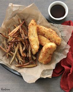 fried fish and french fries on a plate next to a cup of coffee