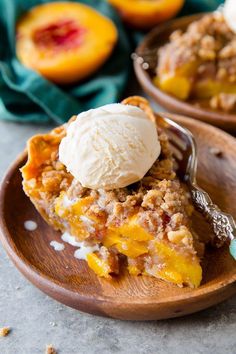 a slice of peach cobbler with ice cream on top in a wooden bowl next to another dish