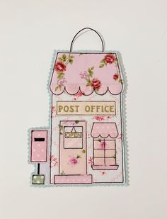 a small pink post office with flowers on the front and side, hanging from a hook