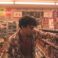 a man is looking at food in a grocery store while he shops for his groceries