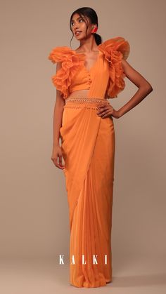 Be the epitome of elegance with our fire orange crepe indo-western saree. The blouse steals the spotlight with its fancy organza ruffle sleeves and alluring V-neckline. Completing the set is a captivating belt adorned with exquisite pearl cutdana and salli embroidery. EVENT - Perfect for cocktail parties festive celebrations and special occasions. Organza Ruffle Sleeves, Cinderella Fashion, Ramadan 2025, Blouses Pattern, Eastern Wear, Dresses Indian Wedding, Fire Orange, Orange Saree