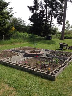 an outdoor garden area with raised beds and flowers in the center, surrounded by trees