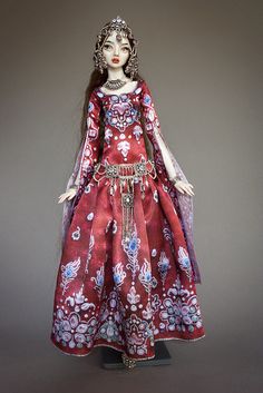 a doll is wearing a red dress with flowers on it