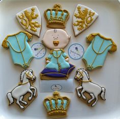 decorated cookies in the shape of royal crowns and horses on a white platter with gold trimmings