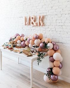 a white table topped with lots of balloons and cake next to a wall that says i & k