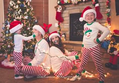 three children dressed up in christmas pajamas and santa hats