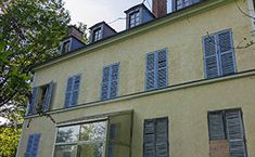 an old building with many windows and shutters on the front, along with trees in the background