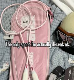 a pair of tennis rackets sitting on top of a bed next to a helmet